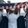 170117-N-BL637-042 A group of U.S. Navy sailors in dress white uniforms are conducting a burial at sea ceremony aboard a naval vessel. They are holding an American flag over what appears to be a casket or remains container at the ship's rail, with open ocean visible in the background. The scene depicts a formal military funeral ritual performed at sea.