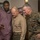 Dexter Fowler Visits the Pentagon Three men are gathered together looking at a smartphone screen in what appears to be a military office or building. Two of the men are wearing U.S. Marine Corps uniforms — one in service khaki and one in MARPAT camouflage — while the third is in civilian clothing. The group appears engaged and focused on content displayed on the phone.