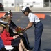 Coast Guardsman presents flowers to a family member during remembrance ceremony