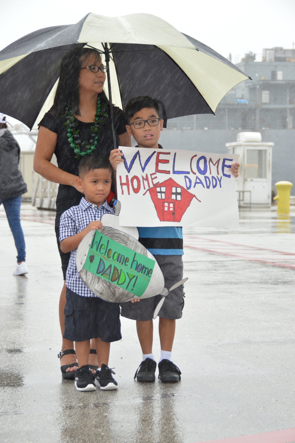 Family Holds 'Welcome Home' Sign for Sailor During USS Topeka Homecoming Jan. 28