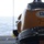 Army Divers plunge into the Pacific during exercise "Deep Blue" The image shows an orange and white underwater or marine equipment unit, marked with the identifier '7-46C', mounted on a metallic bracket on what appears to be the deck of a vessel. A blue inspection sticker from 'Oceaneering Inc.' is visible on the unit's surface. The open ocean is visible in the background, confirming the maritime setting.