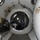 Army Divers plunge into the Pacific during exercise "Deep Blue" The image shows the interior of a hyperbaric or pressure chamber facility, viewed from inside one chamber looking through a circular hatch into an adjacent chamber. The chambers are constructed of thick white-painted steel with circular porthole windows and brass/stainless steel plumbing fittings. Various equipment, cables, and breathing apparatus components are visible throughout the space.