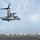 Group Sails A U.S. Marine Corps MV-22 Osprey tiltrotor aircraft is captured hovering or taking off from the flight deck of a naval vessel, likely an amphibious assault ship. The aircraft's rotors are in helicopter mode (tilted upward), and the landing gear is deployed. The flight deck markings, safety equipment containers, and fire suppression labels are visible in the background.