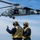 USS America conducts ammo on-load A U.S. Navy MH-60S Seahawk helicopter from HSC-23 squadron hovers above a ship's flight deck while two deck crew members in yellow safety vests and helmets direct the aircraft. The helicopter bears the number 46 and 'NAVY' markings along with a playing card spade insignia on the tail. The scene depicts a routine flight deck operation, likely aboard an amphibious assault ship (LHA).