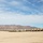 Defense Logistics Agency three star visits MCLB Barstow A large formation of military wheeled vehicles, appearing to be HMMWVs (Humvees) or similar tactical vehicles, are parked in organized rows on a flat desert terrain. The vehicles are painted in a tan/desert camouflage scheme consistent with U.S. military equipment. A mountain range is visible in the background under a partly cloudy sky, suggesting a southwestern U.S. desert environment such as the Mojave or Sonoran Desert.