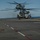 170214-N-NJ910-0188 Two large military helicopters, numbered 43 and 52, are on the flight deck of a naval vessel, with rotor blades spinning. Deck crew members in yellow and blue vests are positioned around the aircraft, indicating active flight operations. The scene takes place on a clear day over open ocean.