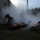 2nd Medical Bn keeps more than knowledge alive A military or emergency response training exercise is taking place outdoors at dusk near a building. Personnel in military/tactical gear are attending to mannequins or training dummies on litters/stretchers amid heavy smoke or fog. The scene depicts a mass casualty response drill with multiple simulated casualties being treated simultaneously.