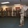 Soldiers and Airmen participate in US Army Japans best warrior competition in Okinawa A senior military officer in U.S. Army OCP (Operational Camouflage Pattern) uniform is addressing a formation of soldiers standing at ease in an indoor facility. The speaker appears to be conducting a briefing or informal address to a group of approximately 20-30 uniformed personnel. The setting appears to be a military building such as a readiness center or armory.