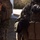 Frag out; Marines participate in grenade assault course The image shows two military personnel wearing MARPAT (Marine pattern) camouflage uniforms in close proximity. One individual is wearing tactical body armor with MOLLE webbing and pouches, along with black tactical gloves. The scene appears to be outdoors during daylight, possibly during a training exercise or operational briefing.