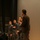 170214-N-XF155-137 The image shows several individuals in U.S. Navy Working Uniform (NWU Type I, blue digital camouflage pattern) standing on what appears to be a stage or auditorium floor. One person in civilian dark clothing is holding a microphone and appears to be speaking or presenting. The image is rotated 90 degrees counterclockwise.