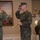 MCIOC Relief and Appointment Three U.S. Marines in MARPAT woodland camouflage uniforms are participating in a formal military ceremony indoors. Two male Marines are exchanging salutes while the center Marine holds a ceremonial NCO sword, suggesting a change of command or promotion ceremony. A female Marine stands at attention to the right as a witness or participant in the ceremony.