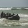 In the CRRC of Time: U.S. Marines and Japanese Soldiers conduct Recon Drills at Exercise Iron Fist A group of personnel in black wetsuits and helmets are navigating a black inflatable rubber boat (IBS/Zodiac-type craft) through rough surf near a shoreline. The individuals appear to be engaged in military or special operations water training, commonly associated with naval special warfare or amphibious assault exercises. Waves are breaking around the vessel as the team works to manage the craft through the surf zone.