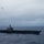 170214-N-FC674-213 A large aircraft carrier is underway at sea under overcast, gray skies. Three military aircraft are flying in formation above and to the left of the vessel. The hull number '70' is visible on the island superstructure, identifying this as USS Carl Vinson (CVN-70), a Nimitz-class nuclear-powered aircraft carrier.