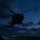 170212-N-HI376-419 A military helicopter is captured in silhouette during twilight or nighttime operations, hovering or taking off from what appears to be a military airfield or flight deck. The scene is predominantly dark with the helicopter backlit against a deep blue dusk sky with scattered clouds. Small green and red lights are visible on the ground and aircraft, suggesting active operations.