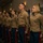 CMC awards Reserve Career Planner of the Year A group of United States Marines stand at attention in a formal indoor setting, wearing their Service Charlie (Dress Charlie) uniforms consisting of khaki shirts and blue trousers with red blood stripes. The personnel are arranged in a line, suggesting a formal ceremony or official military event. Both male and female Marines are present, with visible rank insignia and service ribbons on their uniforms.