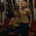 CMC awards Reserve Career Planner of the Year Two U.S. Marines in Service Charlie/Alpha uniforms are present at what appears to be a formal military ceremony. A female Marine is standing at attention wearing a gold hexagonal badge and ribbon rack, while a male Marine is seated behind her. Multiple state and organizational flags are displayed in the background.