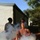 2nd Medical Bn keeps more than knowledge alive A military training exercise is underway in an outdoor setting with smoke obscuring the lower portion of the scene. A soldier in camouflage uniform and combat helmet is carrying or dragging a shirtless training mannequin (casualty simulation dummy) through a smoke-filled area. Additional personnel in military uniforms are visible in the background near a building.
