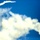 The image shows a large plume of white smoke against a vivid blue sky, consistent with a rocket or missile launch. A fast-moving object with a bright exhaust trail is visible in the upper left portion of the frame, having separated from or ascending above the main smoke cloud. A secondary smoke trail is also visible descending toward the lower right, suggesting possible debris or a separated component.