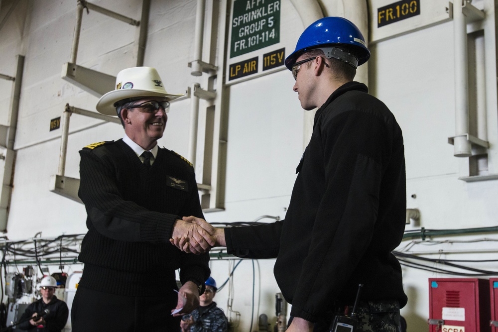 Capt. Buzz Donnell presents a coin to Master-at-Arms 2nd Class Jacob Holt