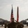 A U.S. Marine in digital camouflage (MARPAT) uniform is rendering a salute on an aircraft flight line during what appears to be a formal military ceremony. Two F-35 fighter jets are visible in the background flanking the formation, along with the U.S. national flag and a red-and-gold Marine Corps unit guidon. Several other Marines are standing at attention or saluting in formation.