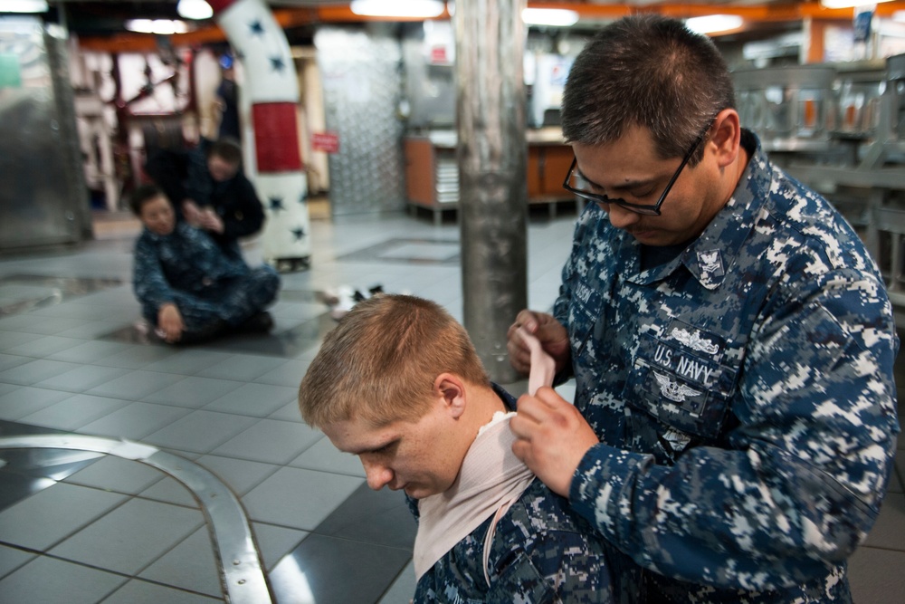 Logistics Specialist applies a pressure dressing to the neck of Operations Specialist Seaman Joshua Hansen