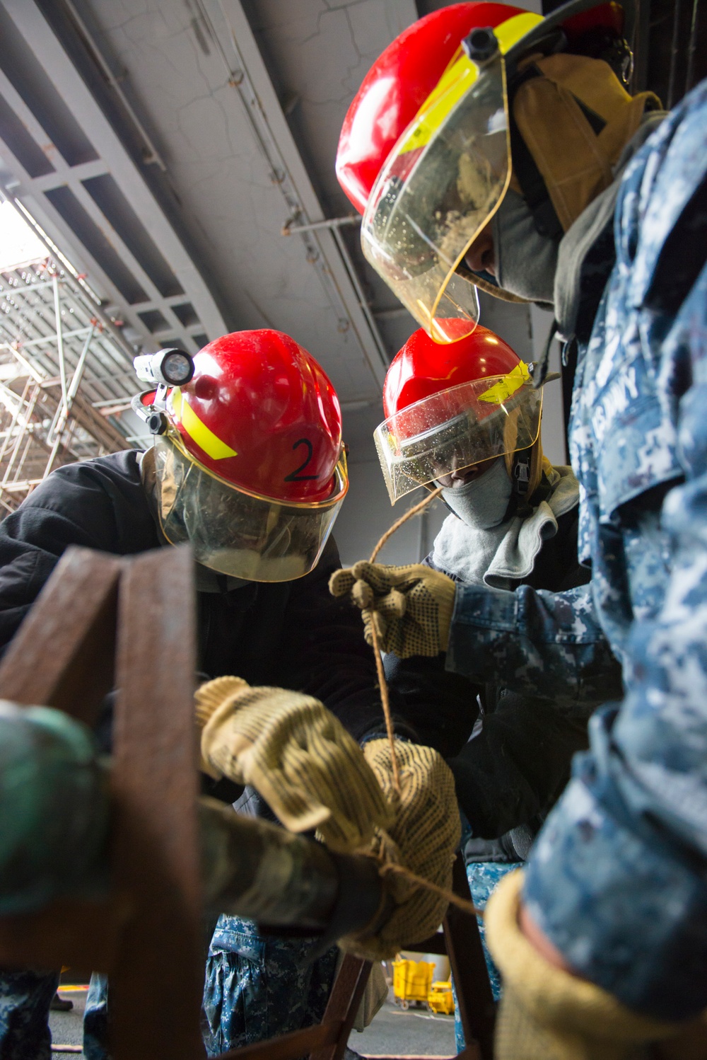 Sailors Use Rope to Secure a Soft Patch to a Pipe During Pipe-Patching Training