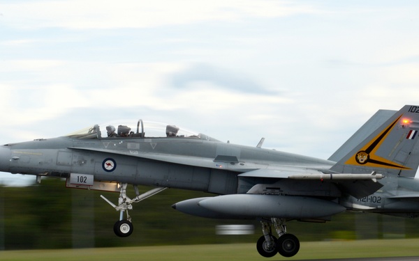 A Royal Australian Air Force (RAAF) F/A-18 Hornet fighter jet, marked with serial number A21-102 and tactical number 102, is captured during a low-altitude takeoff or landing on a runway. The aircraft features distinctive RAAF roundel markings and a yellow/black tail decoration, suggesting a special or commemorative livery. The image uses a panning technique, creating motion blur in the background while keeping the aircraft relatively sharp.