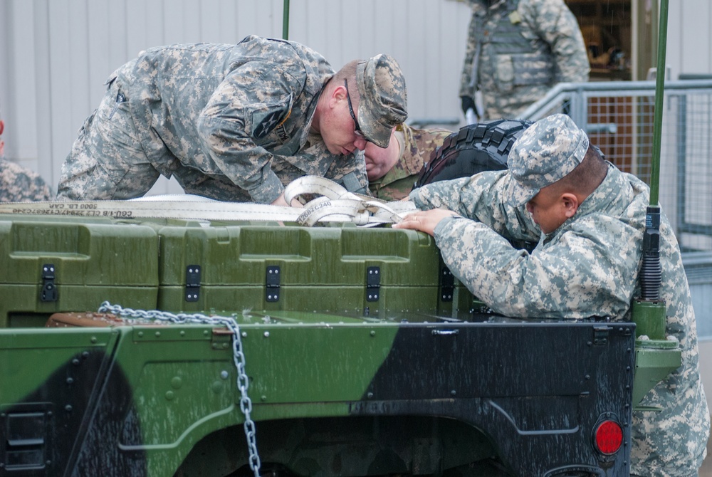 Soldiers from Headquarters and Headquarters Company, 301st Maneuver Enhancement Brigade, prepare a truck to carry cargo before a convoy departs