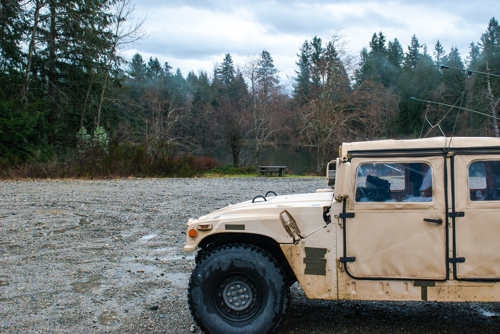A high mobility multipurpose wheeled vehicle (HMMWV) sits parked in front of Sequalitchew Lake