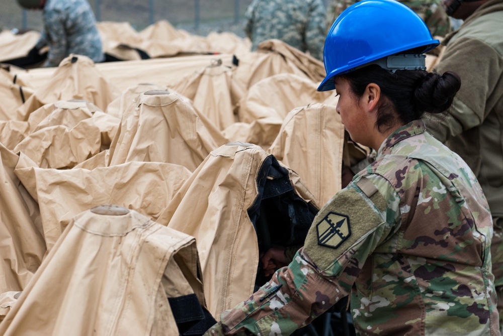 A soldier disassembles a deployable rapid assembly shelter