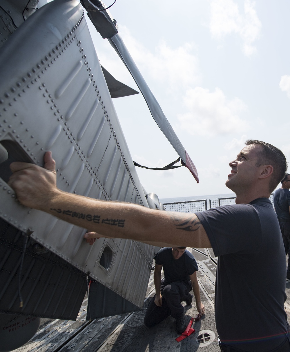 Aviation Ordnanceman 2nd Class Class Sean O’Hara folds the stab of an MH-60R helicopter Aboard USS Michael Murphy (DDG 112)