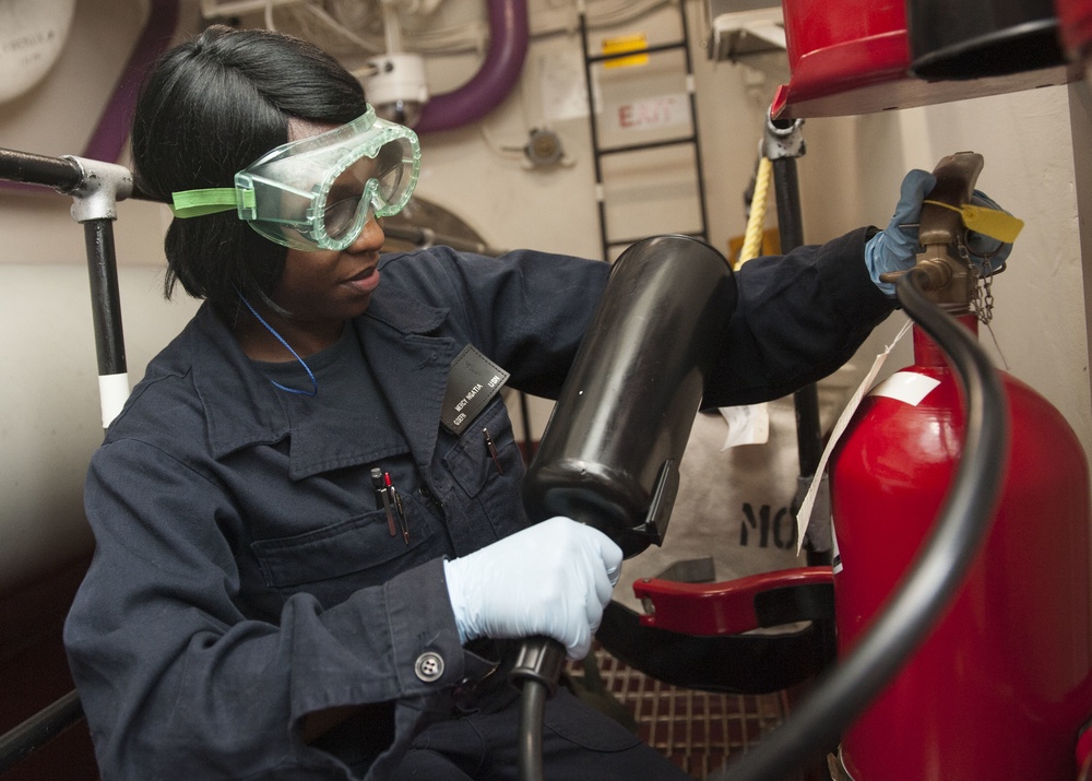 Fireman Mercy Ngatia Conducts Maintenance on a Potassium Bicarbonate Fire Extinguisher