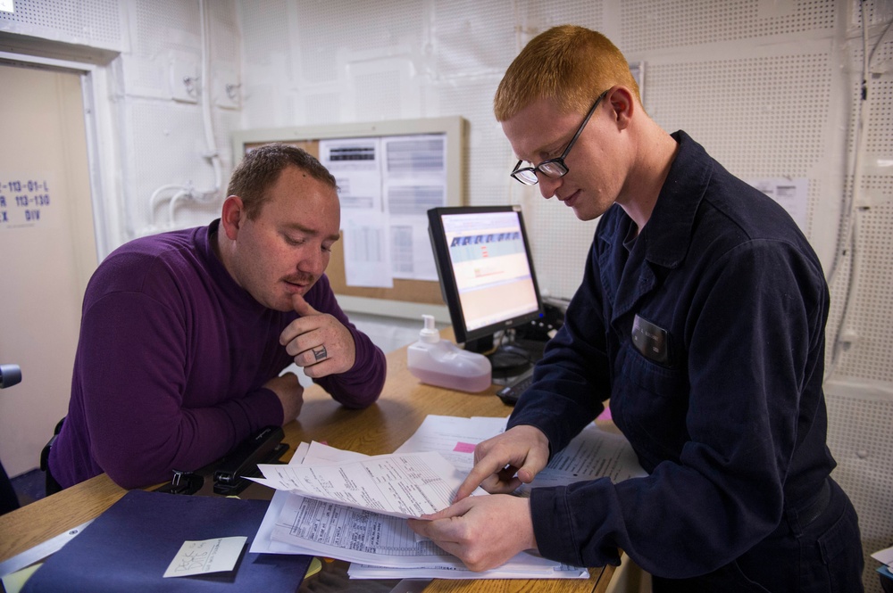 Personnel Specialist Seaman Cody Burkhart assists Aviation Boatswain’s Mate 3rd Class Jeremy Pollard with Paperwork On Board USS America