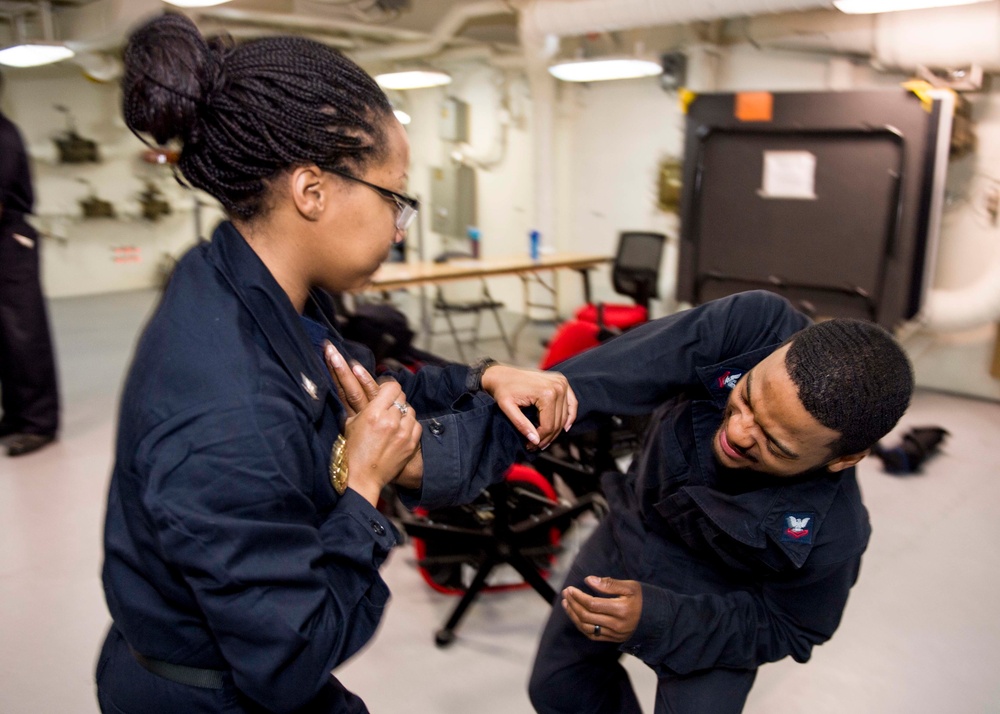 Aviation Electronics Technician 3rd Class Aaron Searcy (right) and Master-at-Arms 3rd Class Deja Otoki (left) perform take down techniques during self-defense training