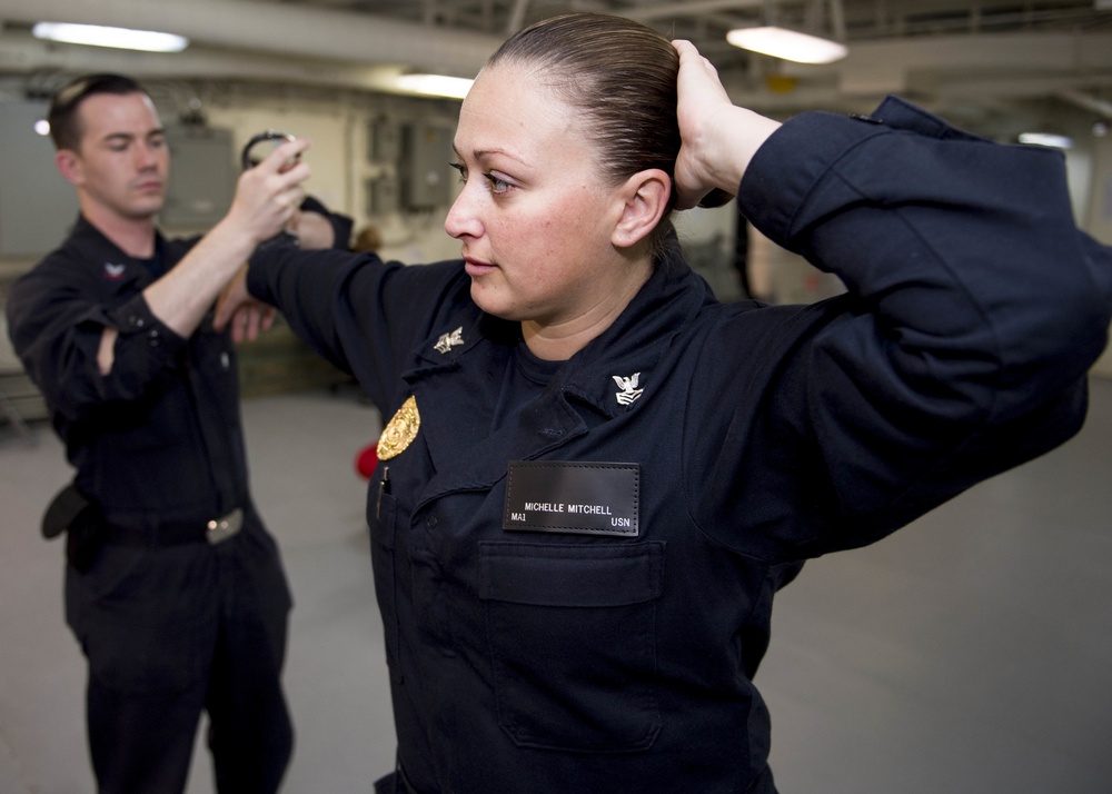 Master-at-Arms 1st Class Michelle Mitchell and Master-at-Arms 2nd Class Joshua Mcconchie perform proper handcuffing techniques during a self defense training exercise