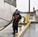 Coast Guardsman drags mooring line down pier