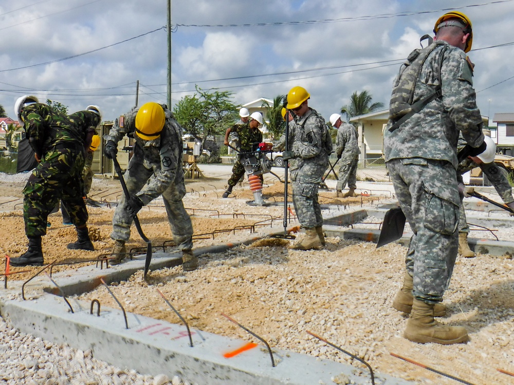 Soldiers with the 672nd Engineer Company work with soldiers with the Belize Defense Force to spread and compact gravel