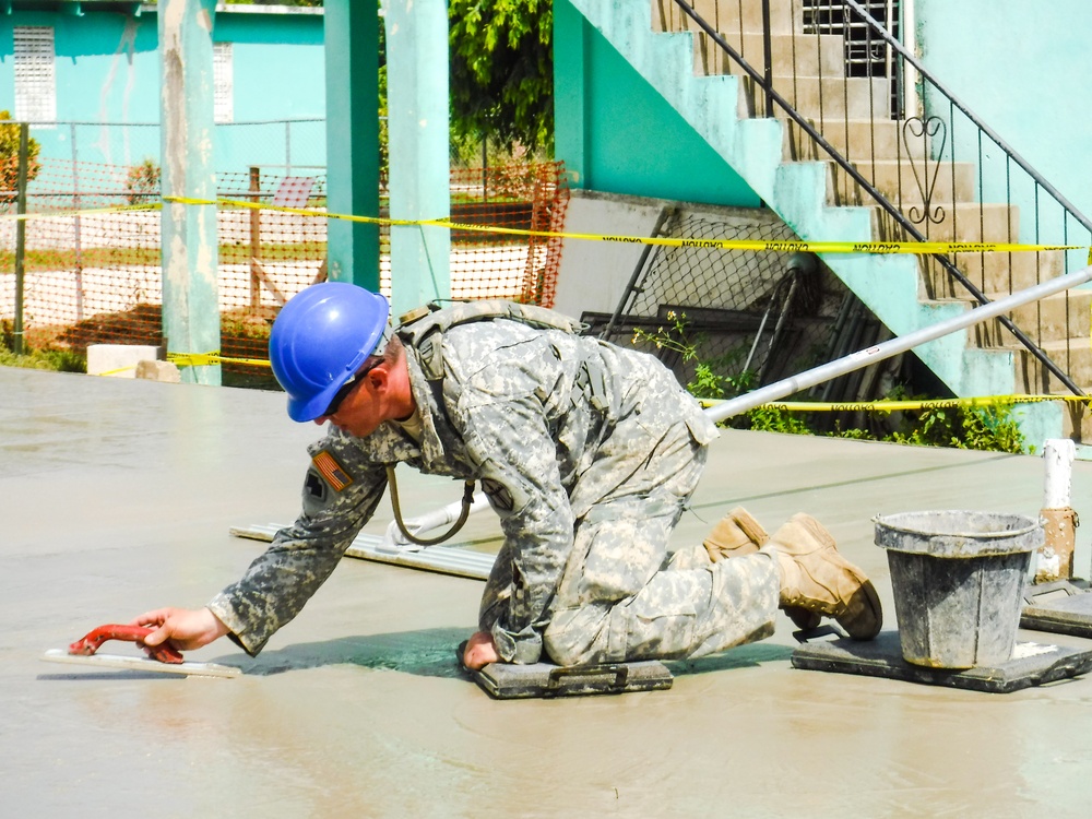 Chief Warrant Officer 2 Steven Heavrin uses a trowel to smooth a concrete slab to perfection