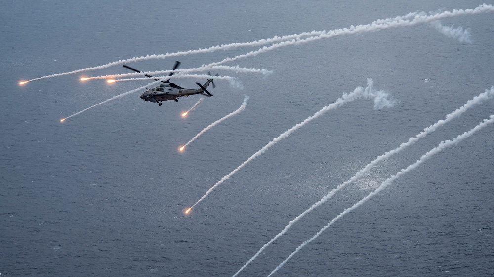 An MH-60R Sea Hawk from the Helicopter Maritime Strike Squadron (HSM) 78 “Blue Hawks” fires chaff flares during a training exercise near the aircraft carrier USS Carl Vinson (CVN 70).