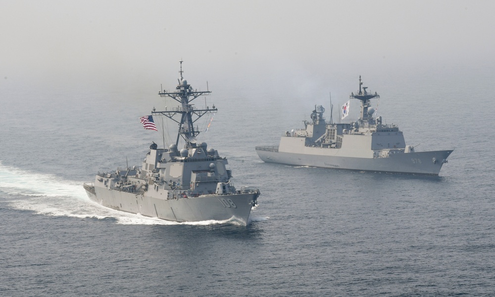 Two military warships are sailing in formation on open ocean waters under hazy atmospheric conditions. The foreground vessel is a US Navy Arleigh Burke-class guided-missile destroyer flying the American flag, bearing hull number 109. The background vessel is a Republic of Korea Navy destroyer flying the South Korean flag, indicating a joint naval exercise or patrol operation.