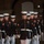 Marine Barracks Washington Evening Parade April 28, 2017 A formation of United States Marines marching in dress blue uniforms during what appears to be a formal evening parade or ceremonial drill. The Marines are in precise formation, wearing their distinctive dress blues with white covers, white gloves, and white trousers. At least one Marine in the foreground is carrying a rifle, and service ribbons and rank insignia are visible on multiple uniforms.