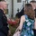 Marine Barracks Washington Evening Parade April 28, 2017 A group of people are gathered outdoors near a white building, likely at a formal military social event. At least two individuals are wearing dark military dress uniforms with visible medals and insignia. Civilians in formal attire are mingling with the uniformed personnel.