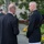 Marine Barracks Washington Evening Parade April 28, 2017 An outdoor gathering at what appears to be a formal government or military event, likely at the White House Rose Garden based on the architecture and landscaping. Two men are engaged in conversation in the foreground — one in a dark civilian suit and one in a dark military dress uniform with medals and a holstered sidearm. Additional military and civilian personnel are visible in the background.