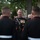 Marine Barracks Washington Evening Parade April 28, 2017 The image shows a group of U.S. Marines in dress blue uniforms gathered at what appears to be an outdoor formal military social event. A senior officer, identifiable by his extensive medal and ribbon display, is engaged in conversation with junior Marines. The setting appears to be a garden or grounds of an official building, suggesting a formal reception or ceremony.