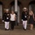 Marine Barracks Washington Evening Parade April 28, 2017 Two U.S. Marine Corps officers in dress blues with white trousers and covers escort two civilian women along a paved walkway at night. The setting appears to be a formal military ceremony or evening parade at a historic brick building with arched architecture. Both officers wear multiple service ribbons and medals, suggesting senior rank.