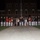 Marine Barracks Washington Evening Parade April 28, 2017 A group photograph taken at night in front of a brick building, featuring U.S. Marines in dress uniforms alongside civilian guests. The Marines are arranged in a line flanking a central group of civilians, suggesting a formal ceremonial event such as an Evening Parade or similar military ceremony. Two Marines in distinctive red ceremonial uniforms are visible among those in standard blue and white dress uniforms.