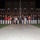 Marine Barracks Washington Evening Parade April 28, 2017 A formal military group photograph taken at night in front of a large brick building, likely a Marine Corps installation. A line of uniformed Marines in dress whites and blues flank a small group of civilians in the center, suggesting an official ceremony or parade event. A bulldog, likely the Marine Corps mascot, is visible on the right side of the formation.