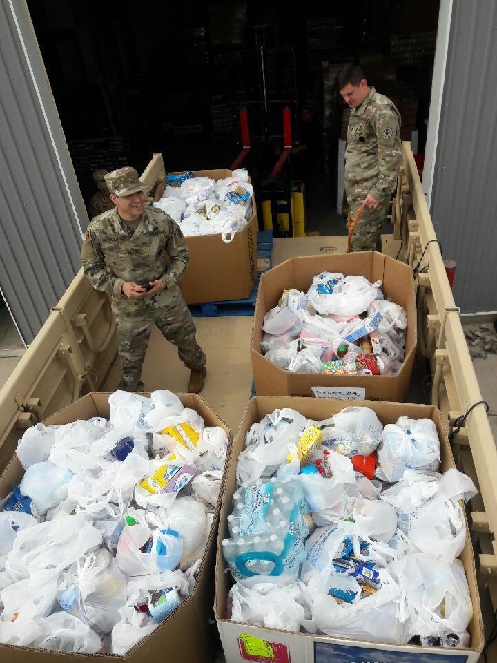 Soldiers unload over 2 tons of food from a light medium tactical vehicle