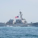 A United States Navy guided-missile destroyer bearing hull number 112 is underway at sea. The vessel is painted in standard naval gray and flies the American flag from its mast. The ship appears to be traveling at moderate speed, generating a visible wake.
