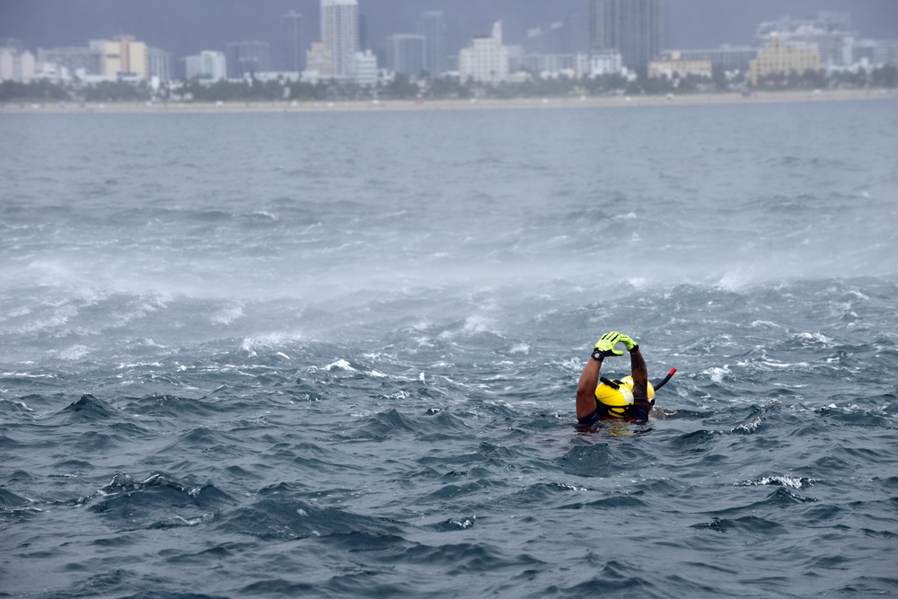 Coast Guard rescue swimmer signals helicopter during mock rescue